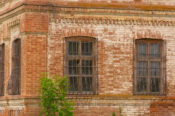 Abandoned house, old windows with bars on a brick old house. The estate of the late 18th century. Residential building of the last century.