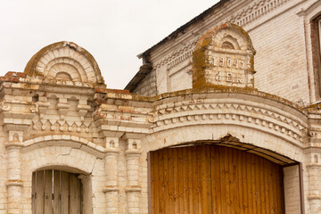 Large wooden gate with an arch. The old gate. Old brickwork with a pattern. The residential building of the last century has 2 floors.