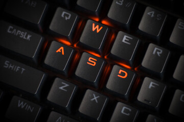 WASD keys light up in orange on RGB mechanical gaming keyboard. WASD keys used for walking in games