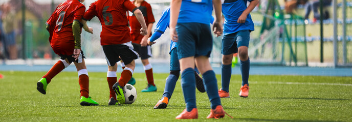 Sporty Football Boys Running After Ball in Duel. Horizontal Football Background. School Soccer Competition Between Junior Level Players. Multi-ethnic Kids Play Sports