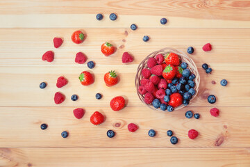 Naklejka na ściany i meble Berries in wicker basket and near on wooden table