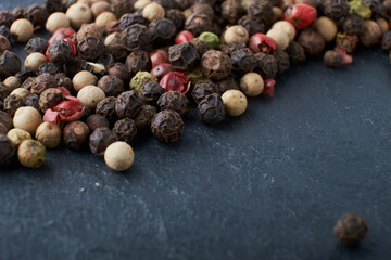 A mixture of peppers. Black, white, red polka dots. Isolated on a stone background. The selected sharpness
