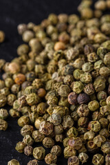 green peppercorns on dark slate stone background
