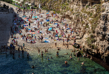  People relax and swimming on lovely beach Lama Monachile in Polignano a Mare, Adriatic Sea, Apulia, Bari province, Italy,