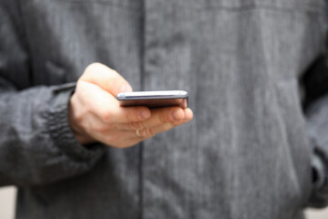 Closeup man in jacket holds smartphone his hands