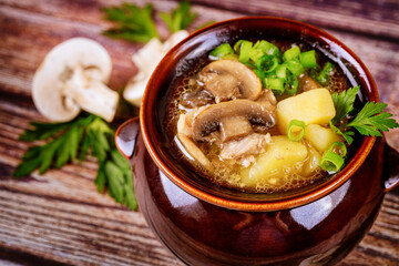 Mushroom soup with potatoes and chives in a clay pot.
