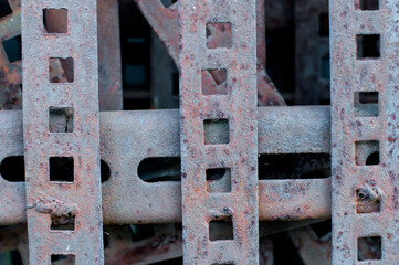 Rusty brown metal picket fence with square windows.