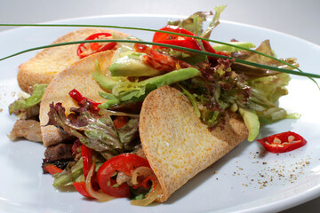 Tacos with avocado, lettuce and pepper on a white plate
