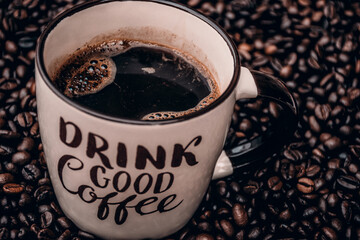 mug filled with black coffee and coffee beans in the background