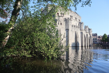 Scenic panorama of the ancient castle Gravensteen, Ghent, Belgium, the old fortress, view from the river, reflected in the water.

