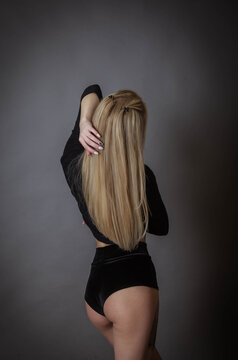 the blonde beauty poses in a black bodysuit with her back to the wall and showing off her gorgeous hair