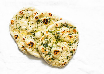 Garlicky herbs butter flatbread naan on a light background, top view