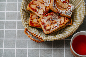 puff pastry puffs with Apple in a wicker basket, cinnamon and powdered sugar, tea