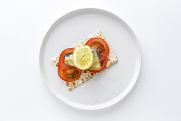Salty crackers with sardine, tomato and lemon from above