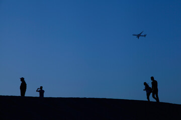 Fototapeta na wymiar silhouette of family in Dubai desert with airplane flying
