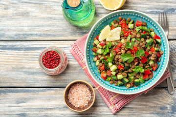 Lentil salad with cucumber, bell pepper and coriander leaves on rustic wooden table