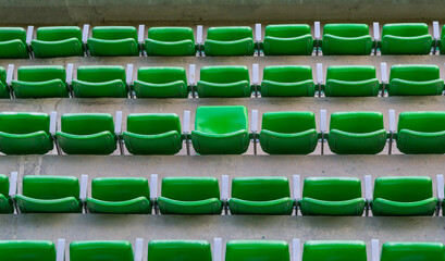four rows of green plastic seats inside stadium, all folded but one