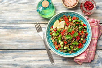 Lentil salad with cucumber, bell pepper and coriander leaves on rustic wooden table