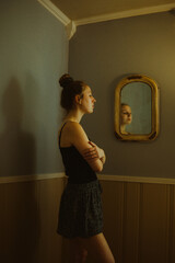 Young woman standing indoors with mirror in the background 