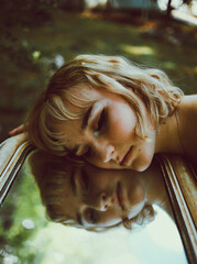 Portrait of young woman lying down on a mirror 