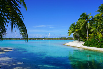 View of a tropical landscape with palm trees, white sand and the turquoise lagoon water in Bora...