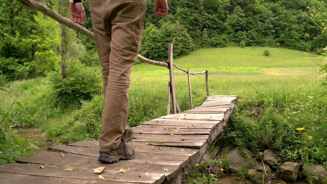 Image of man crossing small wooden bridge at Zumberal national park.