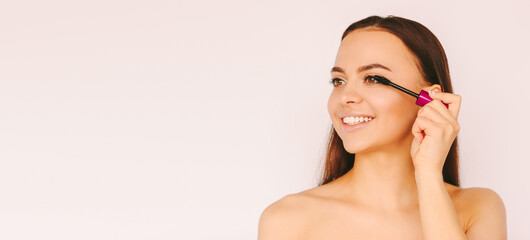 Portrait young happy girl apply mascara for long eyelashes and smile isolated white background....
