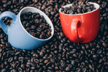 red and blue coffee cups filled and surrounded by coffee beans