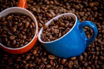 red and blue coffee cups filled and surrounded by coffee beans