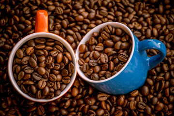 red and blue coffee cups filled and surrounded by coffee beans