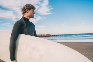 Surfer standing in the ocean with his surfboard.