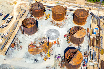Construction of tank for an oil storage by sheet assembly. View from above. Flight around construction site