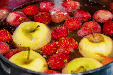 Stewed apples and Strawberry are cooked in a pan. Compote is cooked in a saucepan.