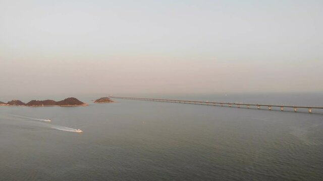 Panning aerial shot of South China Sea and Hong Kong - Zhuhai - Macau Bridge in during golden hour