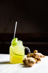 A refreshing summer lemonade with cucumber and ginger in a jar, on white wooden table