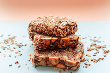 Sliced whole grain bread rye with seeds flax, sunflower, pumpkin and sesame.Healthy food, eco-friendly natural products. Fresh bread on a pink background.