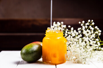 A refreshing mango lemonade in a jar, on white wooden table