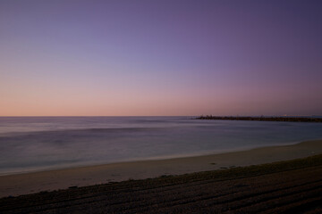 Sunrise on the beach, jetty with fishermen