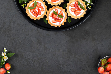 Tartlet with cottage cheese cream and fresh strawberries on a dark background top view