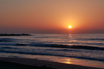 Fototapeta premium Sunrise on the beach, jetty with fishermen