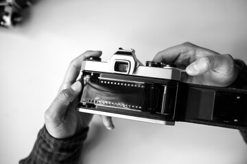 Male man hands reloads film in pentax retro camera on a white table
