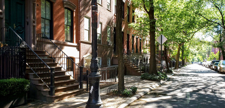 Sunlight shines on a block of historic brownstone buildings in the East Village neighborhood of Manhattan in New York City