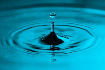 drop of water. Perfect water drop splashing into smooth water causing ripples