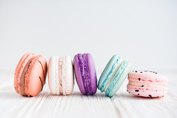 French macaroons in rows on white wooden with white background. Sweet and colorful French macaroons. Dessert. Homemade sweets. Café dessert. Selective focus