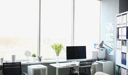 White desk with desktop PC and chair near window in modern office cabinet