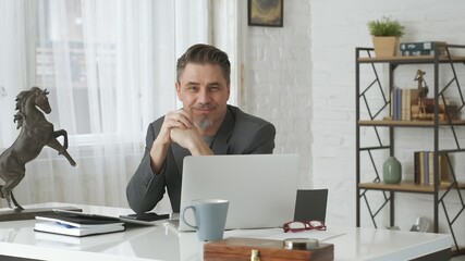 Older man working with laptop computer at home office, thinking, looking busy. 