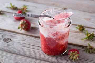 Strawberry with sour cream in jar on wooden table