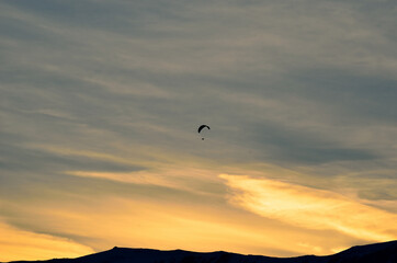 Fototapeta na wymiar paraglider on a beautiful dawn sky with majestic snow covered mountain underneath in the arctic circle