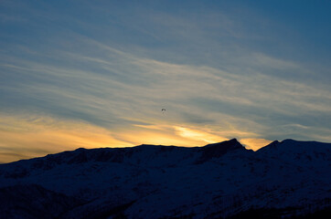 paraglider over snow covered mountain with bright and colourful dawn light in the arctic circle