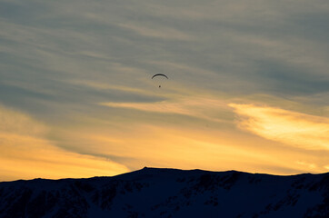 paraglider on a beautiful dawn sky with majestic snow covered mountain underneath in the arctic circle